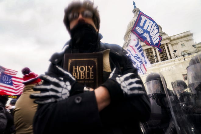 A man holds a Bible in his hand this Wednesday, January 6, 2021 as President Donald Trump's supporters gather outside the Capitol in Washington.