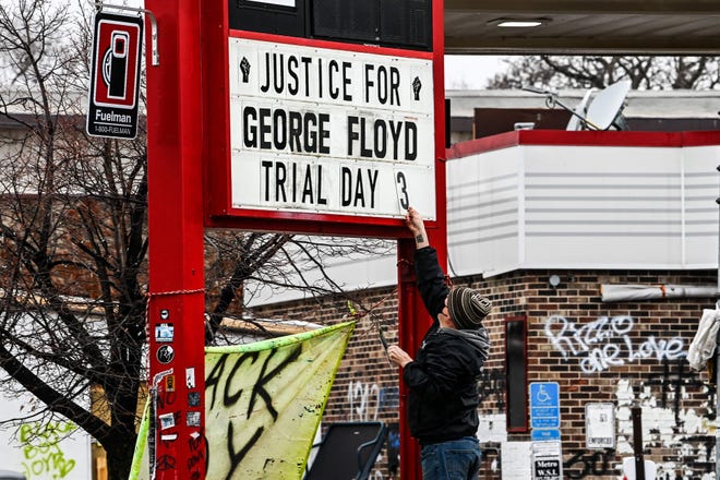 A man changes the number of a placard on a makeshift memorial dedicated to George Floyd before the third day of jury selection begins in the trial of former Minneapolis police officer Derek Chauvin, who is accused of being Floyd on March 10, 2021 in Minneapolis, Minnesota, to have killed.