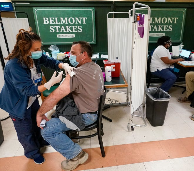 A nurse (left) inoculates a metal worker with a dose of the COVID-19 Pfizer vaccine at a coronavirus vaccination site in Belmont Park in Elmont, New York, Wednesday.