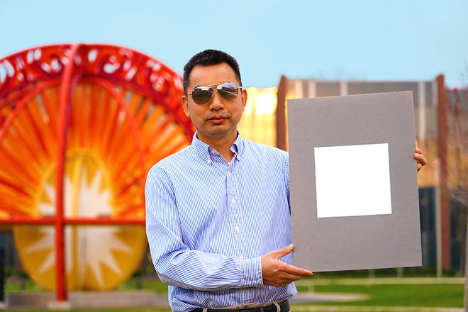 Xiulin Ruan, professor of mechanical engineering at Purdue University, holds up his laboratory sample of the whitest color ever.