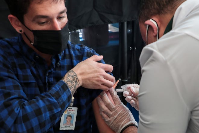 Sean Snider, a paraprofessional educator at Cabot Yerxa Elementary School in Desert Hot Springs, Calif., Receives a Johnson & Johnson COVID-19 vaccine from Rite Aid pharmacy manager Louie Gironella at a Palm Springs vaccination clinic on Wednesday March 10, 2021 Unified School District.
