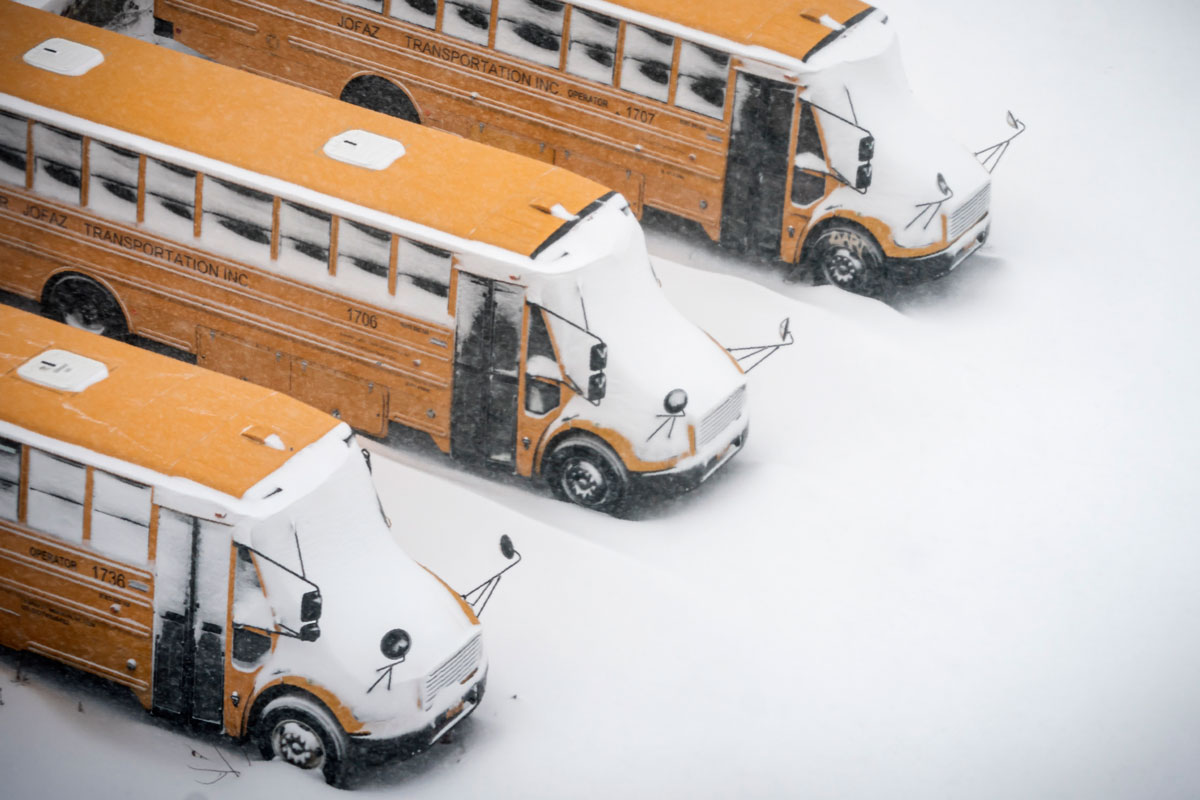 School buses are covered in snow during a snowstorm on February 1 in Brooklyn, New York.