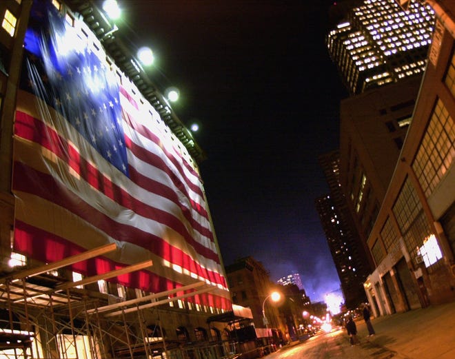 A large flag drapes a building a few blocks north of the smoldering World Trade Center site in New York early Thursday morning, September 27, 2001. The site that was destroyed by the September 11th terrorist attacks is being cleared around the clock.